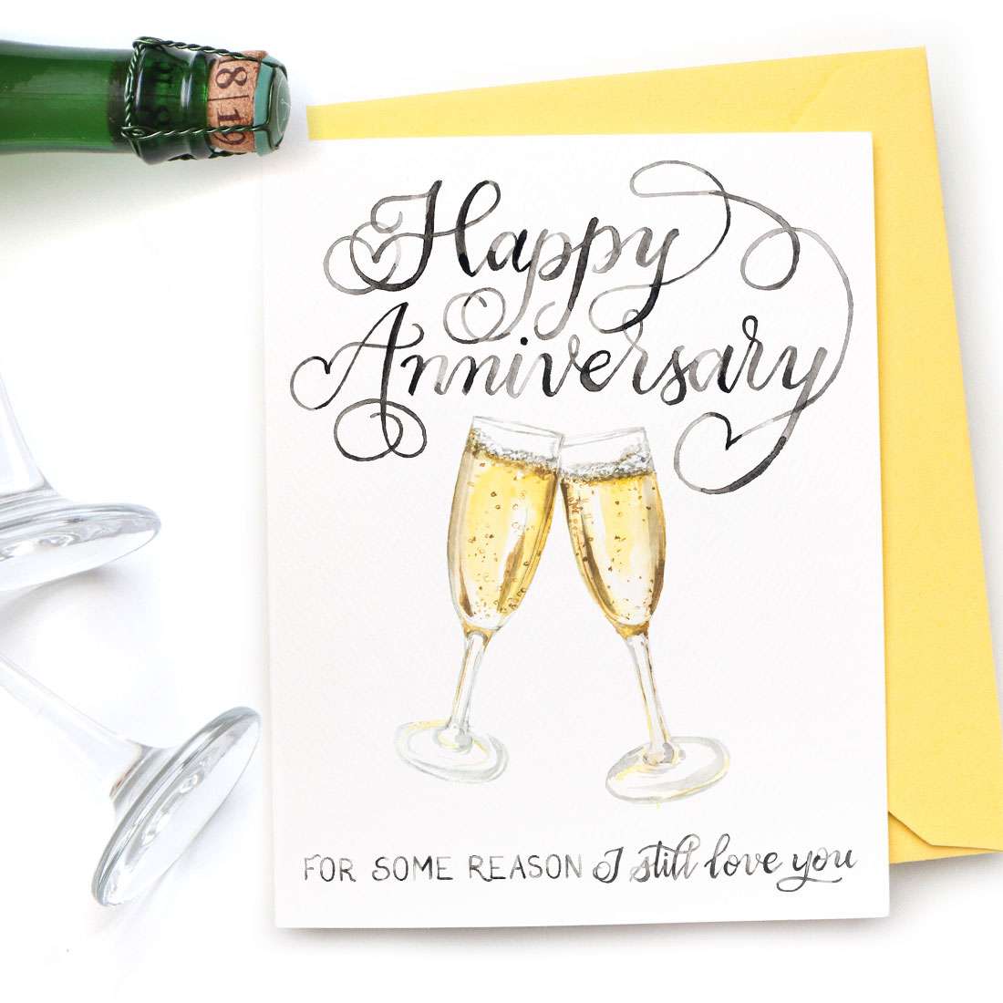 Image of a hand-lettered watercolor card saying "Happy Anniversary" with two painted champagne glasses by CharmCat | charmcat.net