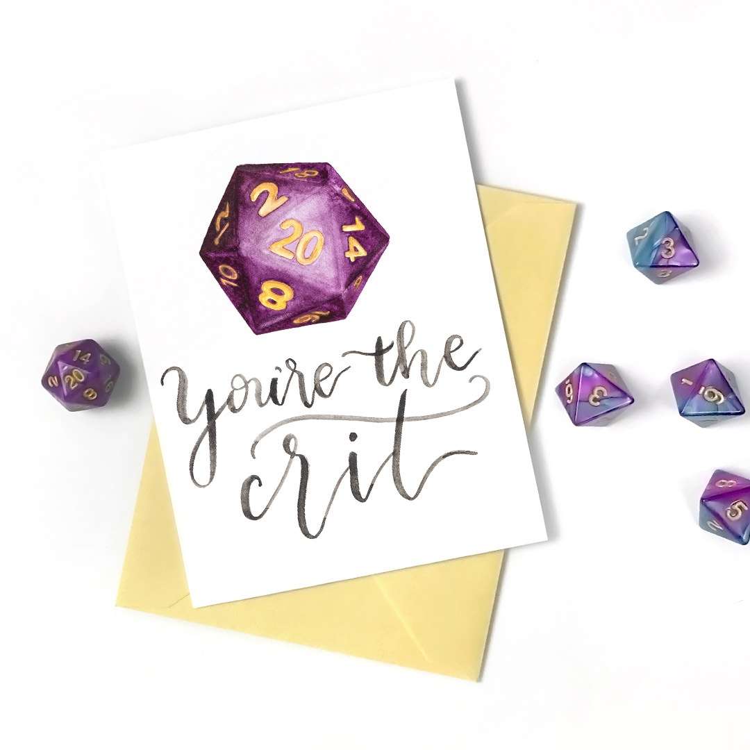 Image of a hand-lettered watercolor card saying "you're the crit!" with a purple D20 dice showing a 20 by CharmCat | charmcat.net