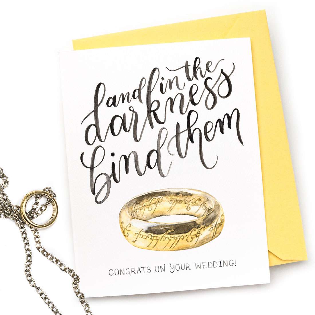 Image of a hand-lettered watercolor card saying "and in the darkness bind them...congrats on your wedding!" with a gold ring by CharmCat | charmcat.net