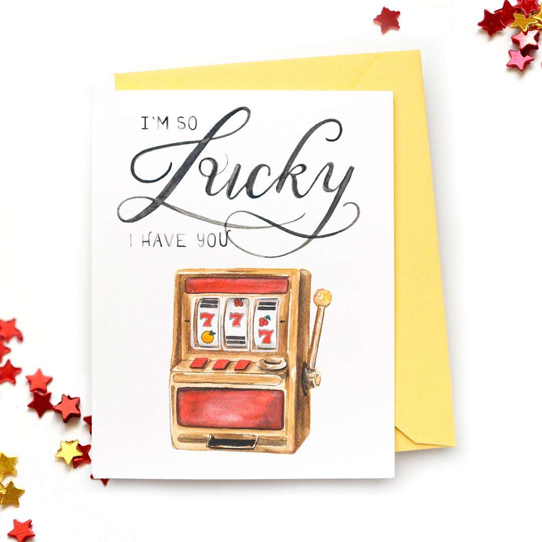 Image of a hand-lettered watercolor card saying "I'm so Lucky I have you" with a painting of a slot machine by CharmCat | charmcat.net