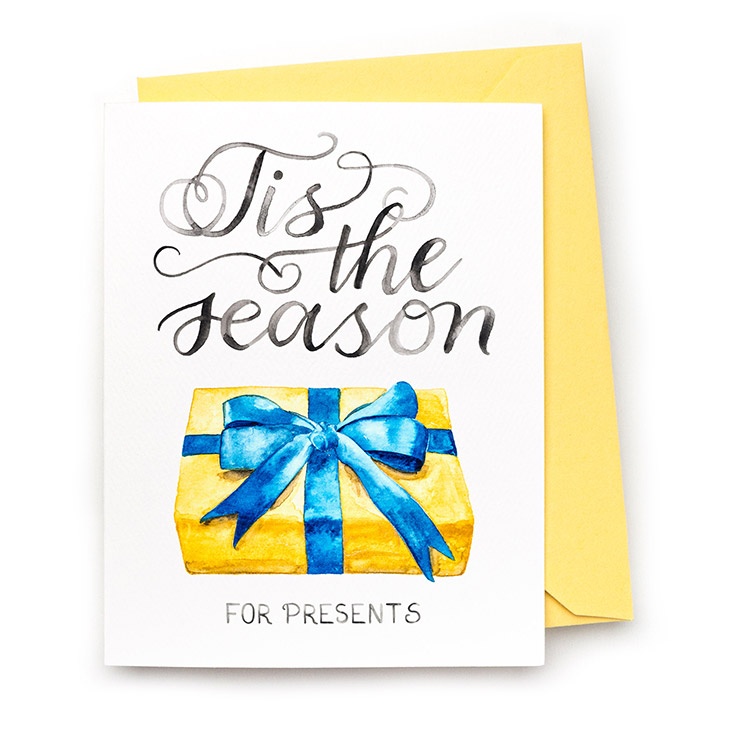 Image of a hand-lettered watercolor card saying "Tis the season... for presents" with a gold and blue wrapped present by CharmCat | charmcat.net