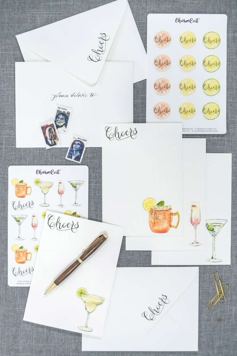 Flay lay of the Cocktails Letter Writing Kit gift box with 12 flat note cards, 12 printed envelopes, 2 sticker sheets, and 1 hand-turned wood pen