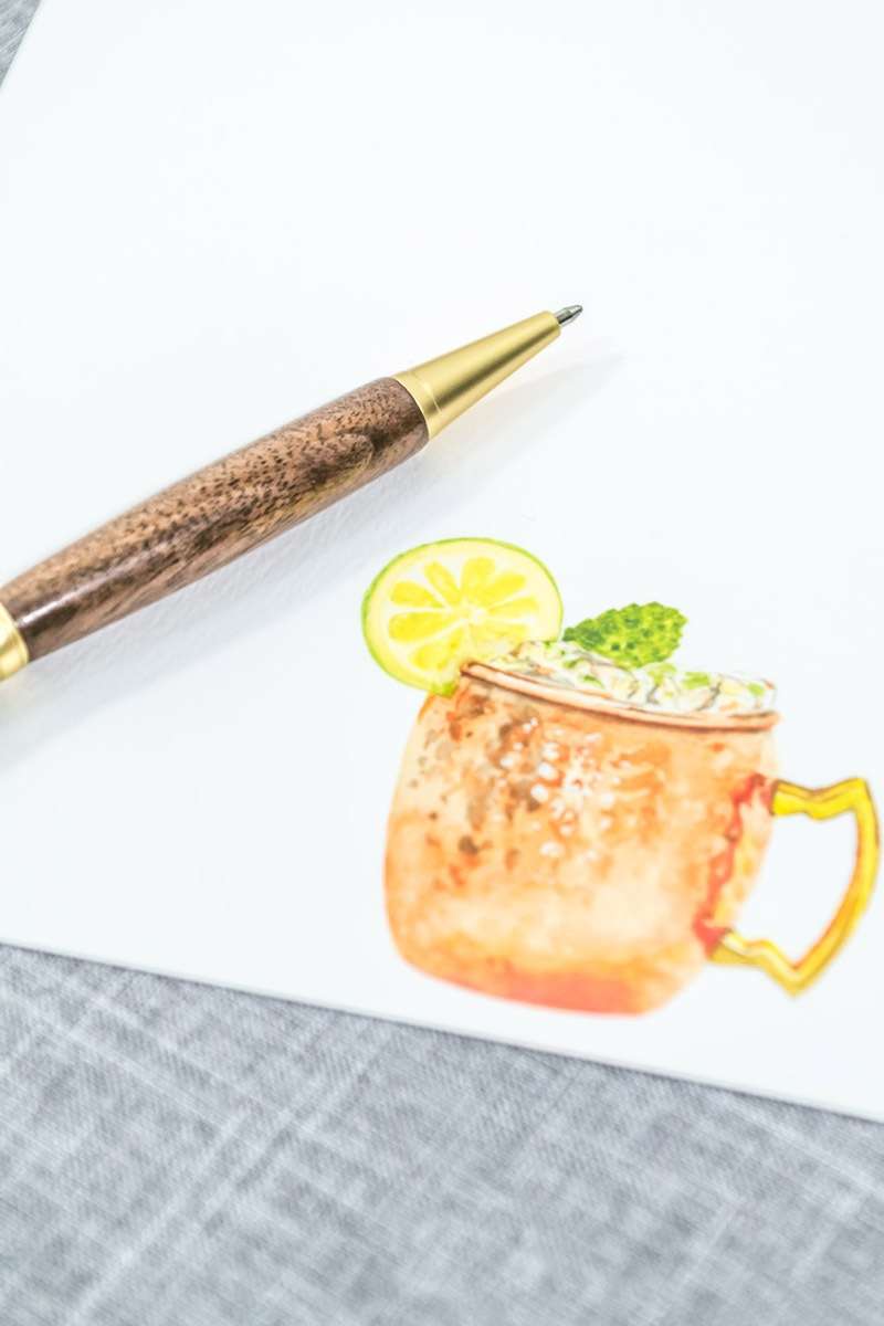 A notecard with a painted moscow mule and a wooden pen.