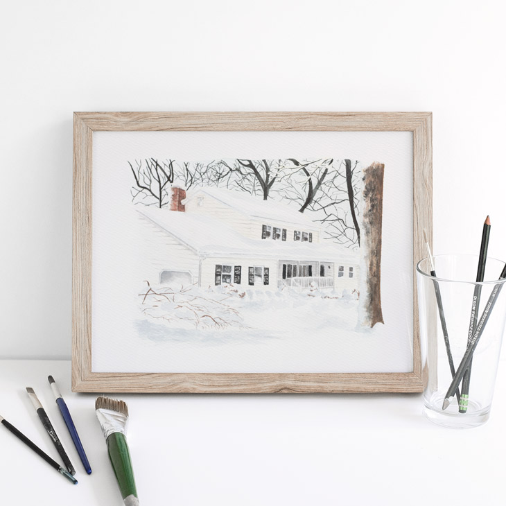 Framed painting of a beige house in the snow with snow-covered trees.